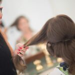 Close-up of hairstylist applying hairspray to brunette client in a salon.