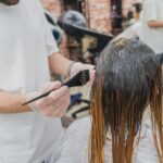 Hair coloring process in a salon, showcasing stylist applying color to client's hair.