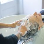 Close-up of senior woman getting hair washed with foam at salon sink, enjoying the pampering session.